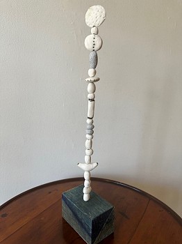 Various forms of porcelain beads are stacked to form a table top totem.